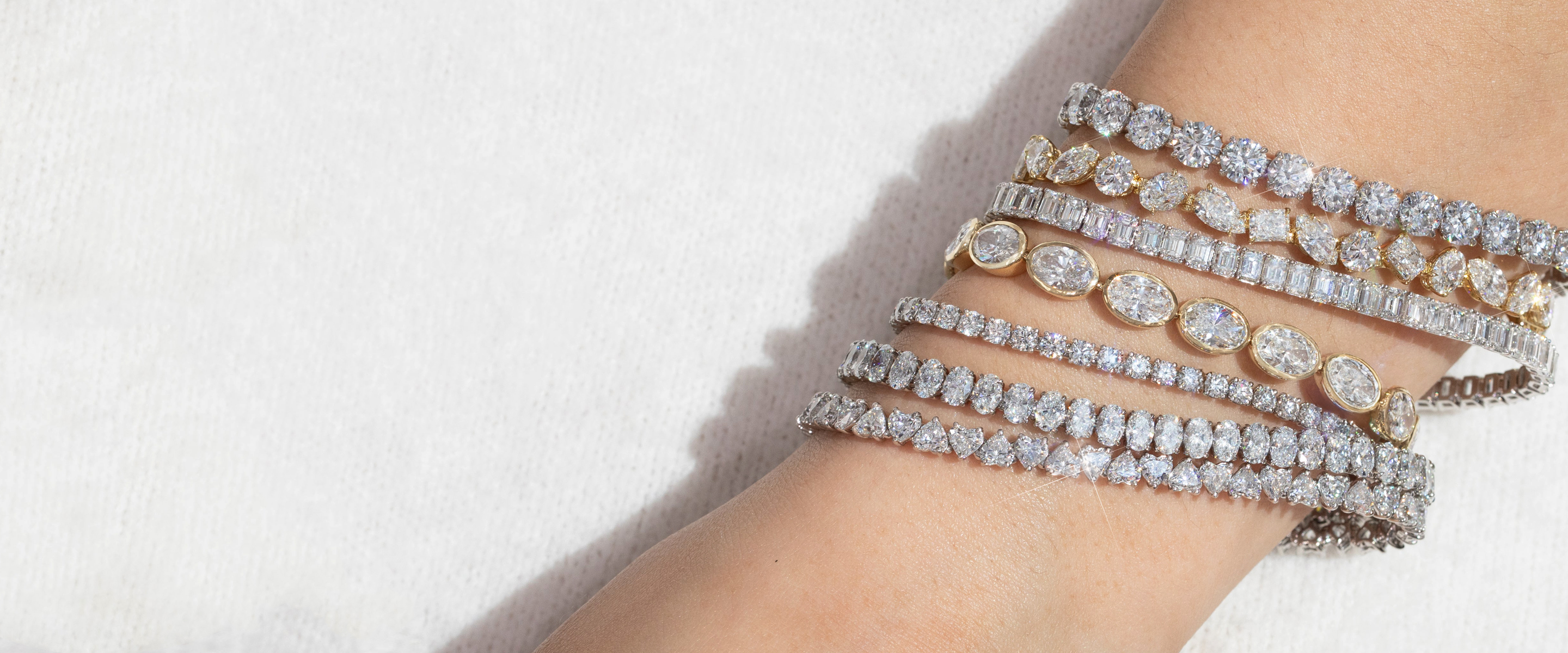 A wrist layered with diamond tennis bracelets in different cuts and settings